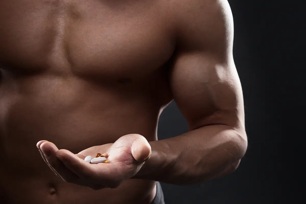 Muscular man holding a handful of supplement pills